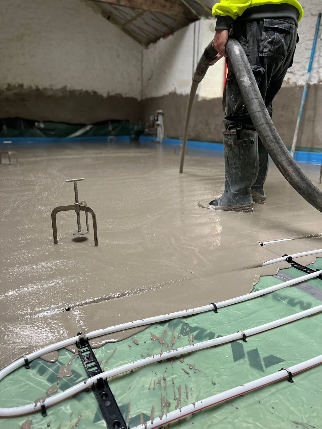 Screed being poured over underfloor heating pipes